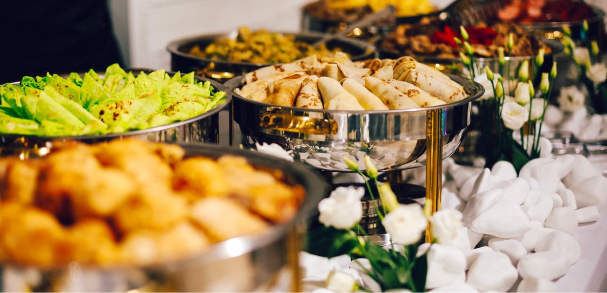 Food in multiple trays in a buffet style setup.