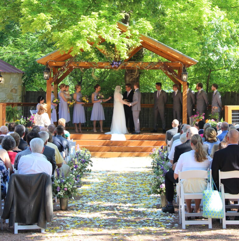 Bride and groom getting married in an outdoor hill country setting, with guests seated.